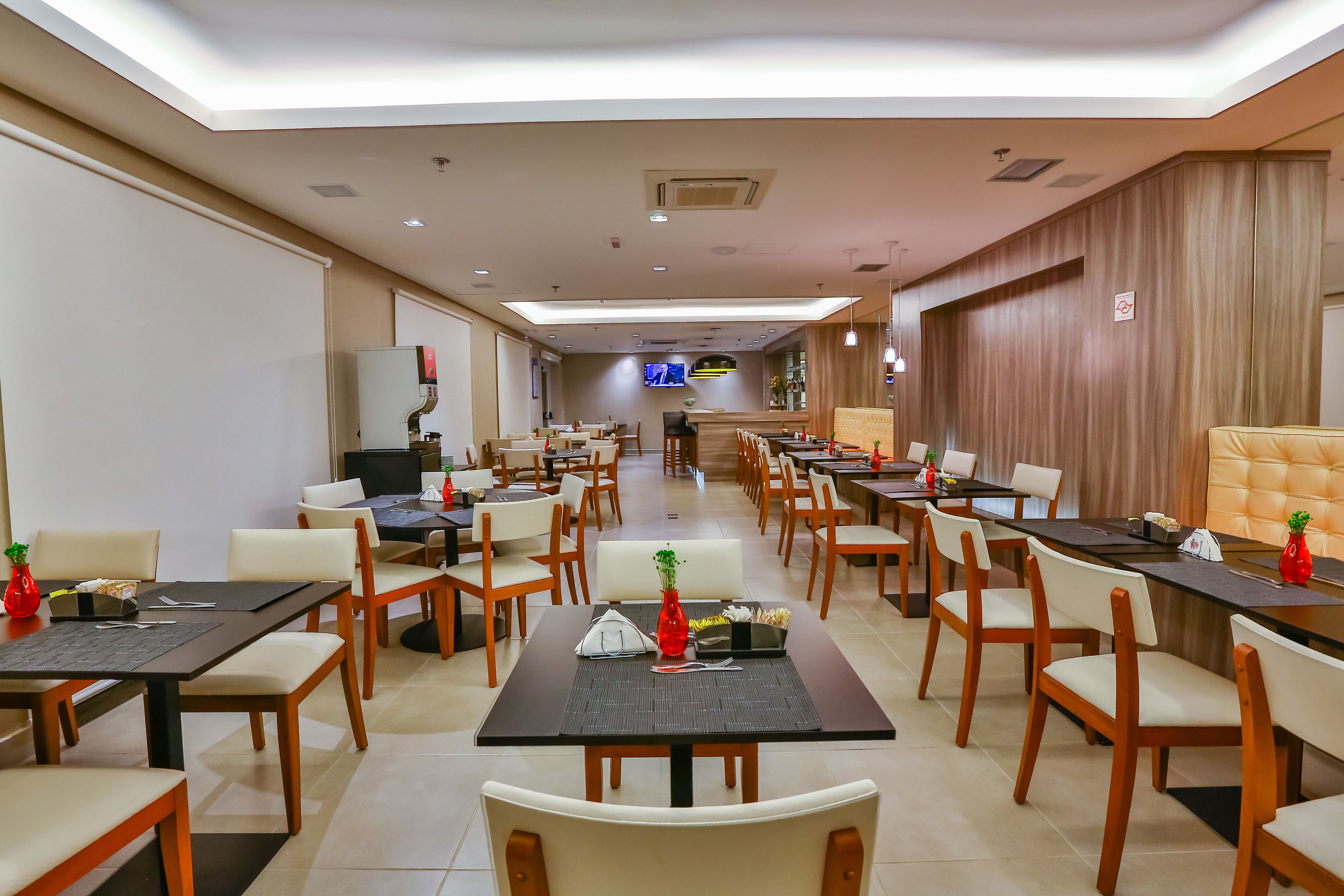 A spacious conference room with multiple tables and chairs, equipped with laptops, a projector, and a television screen.