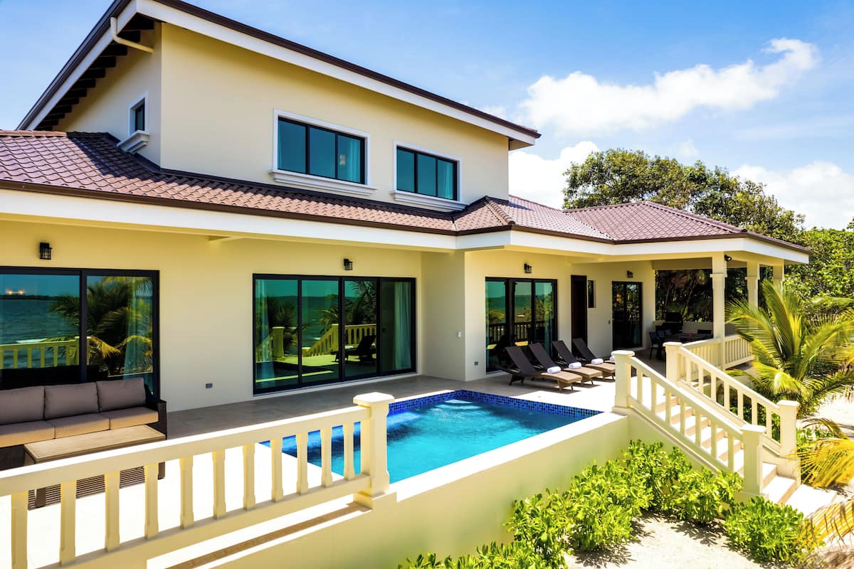 A modern two-story house with a swimming pool, large windows, and a covered patio area.