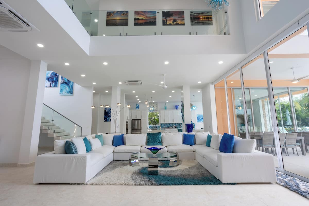 A modern living room with a white sectional sofa, a glass coffee table, and artwork on the walls.