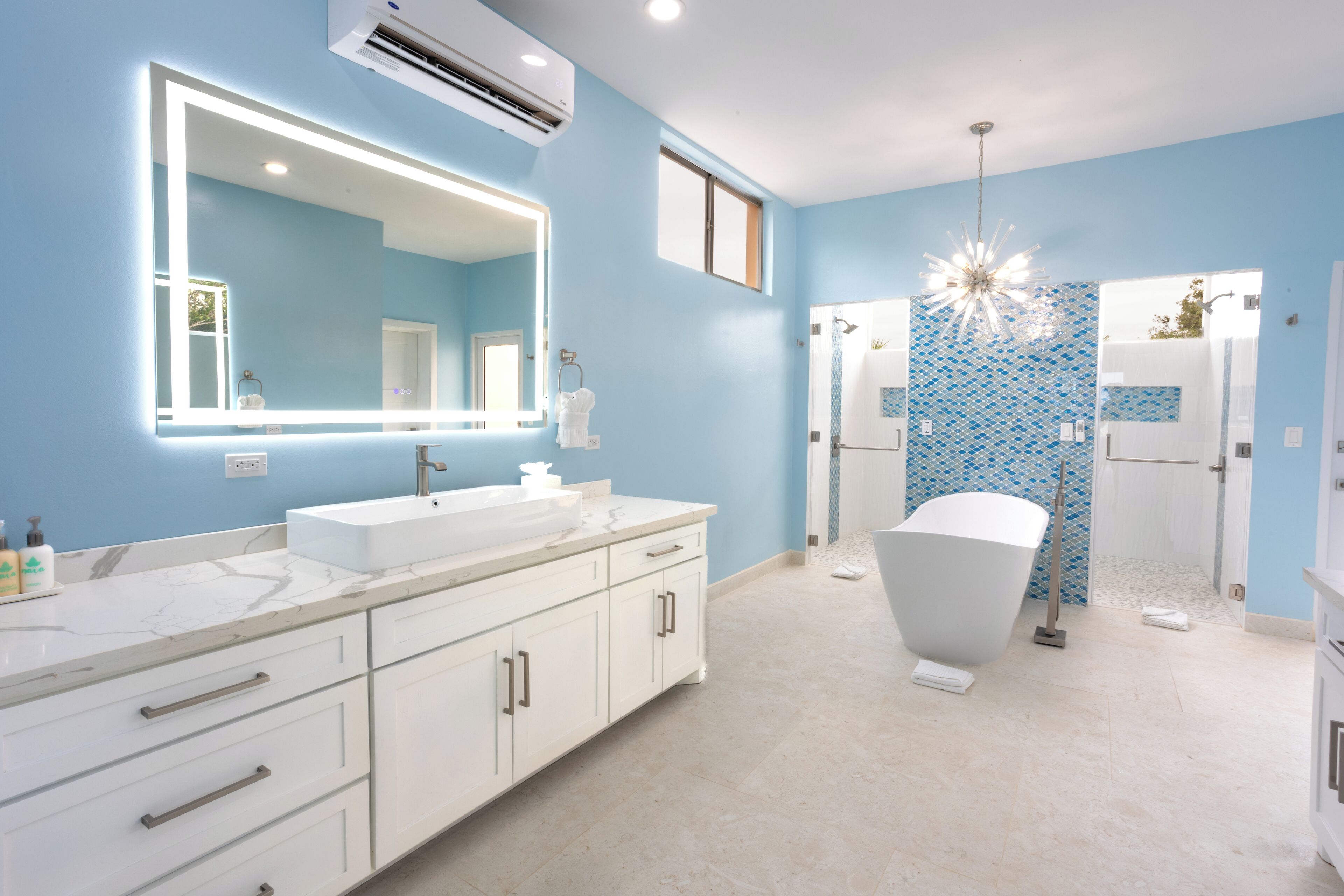 Un baño moderno con un espejo grande, dos lavamanos, una bañera y una zona de ducha.