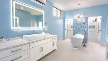 Un baño moderno con un espejo grande, dos lavamanos, una bañera y una zona de ducha.