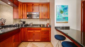 Una cocina con armarios de madera, un microondas de acero inoxidable y un cuadro de una playa.