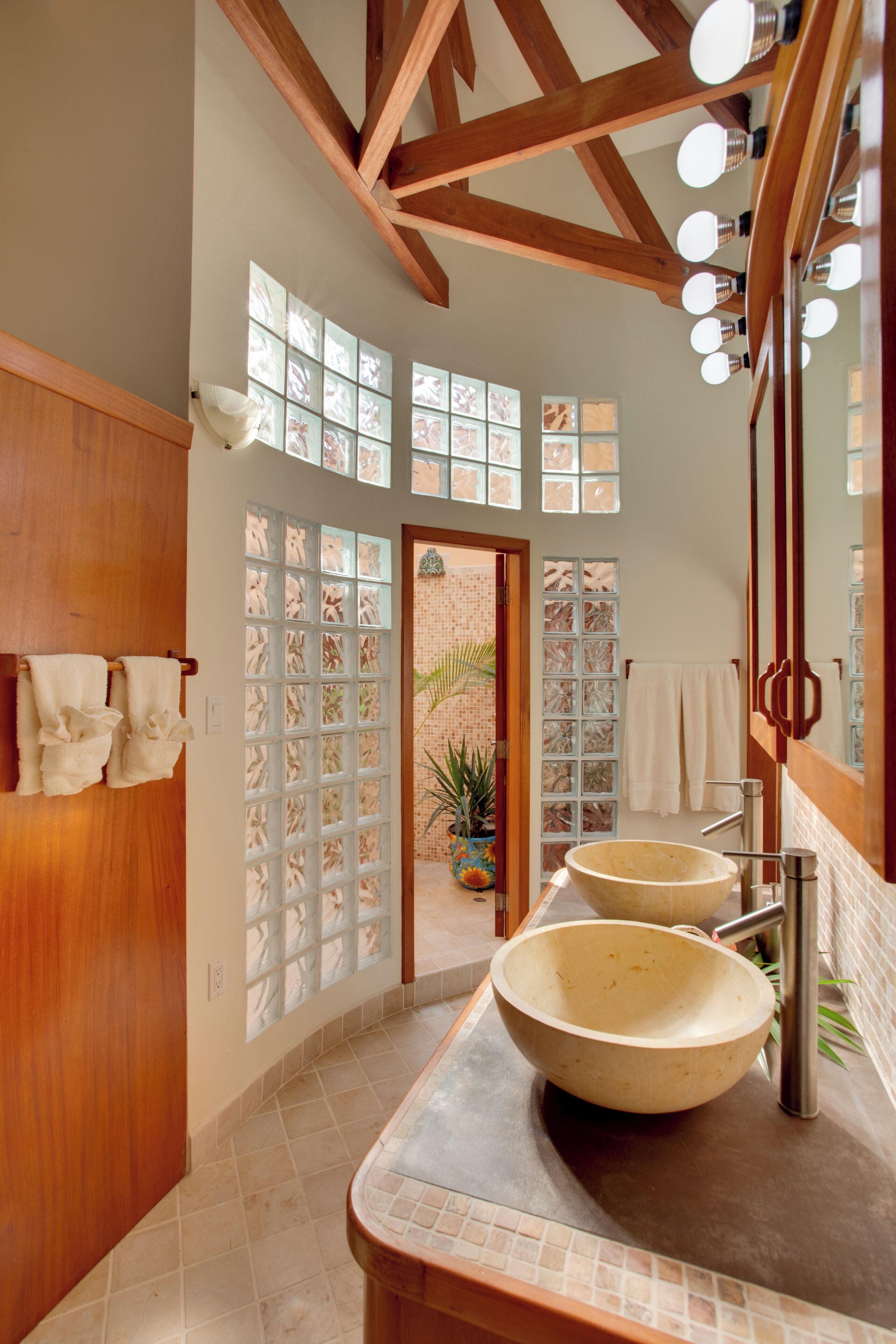 A bathroom with wooden beams, a large window, and two sinks with round bowls.