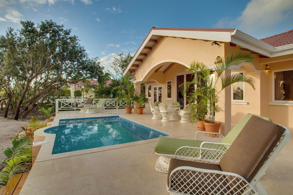 A pool area with lounge chairs, a swimming pool, and potted plants.