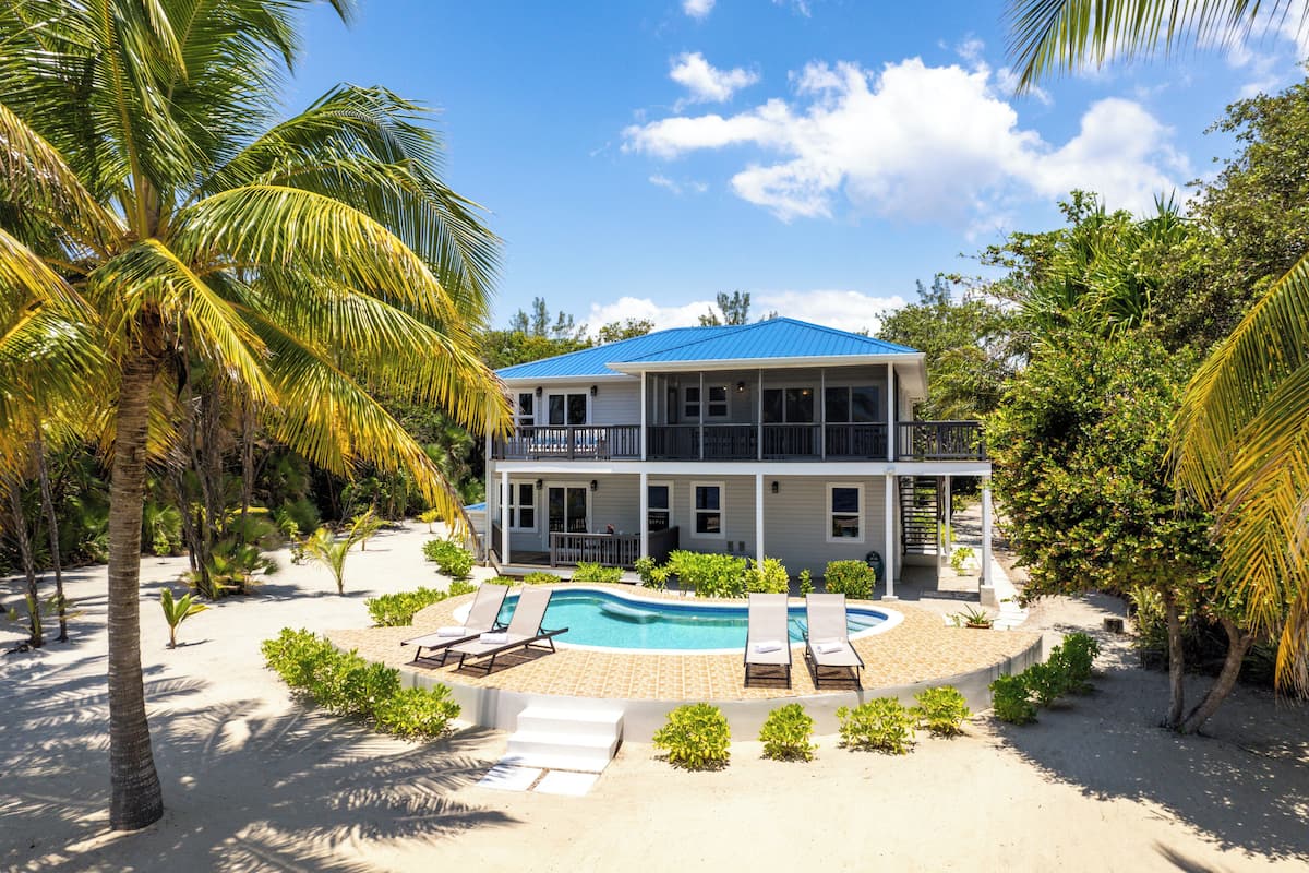 A two-story house with a blue roof, a swimming pool, and a balcony.