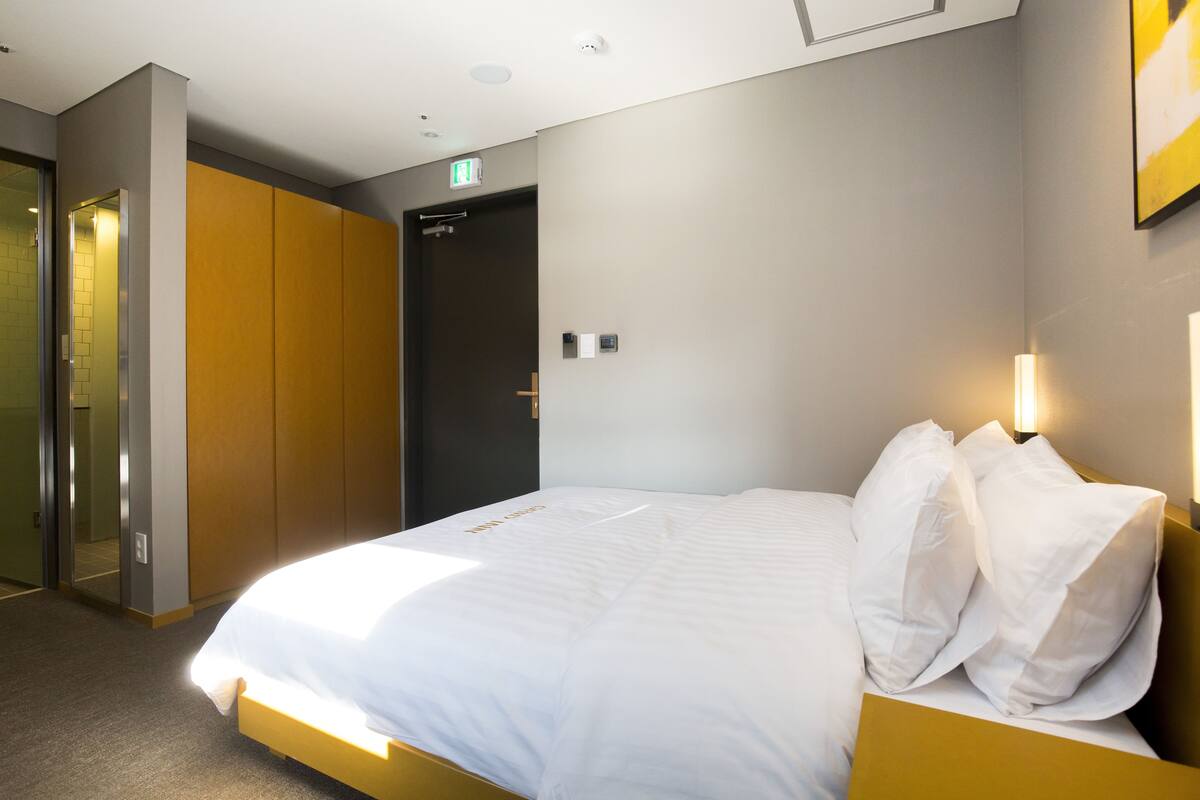 A hotel room with a bed, a wardrobe, and an exit door.