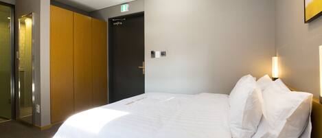 A hotel room with a bed, a wardrobe, and an exit door.