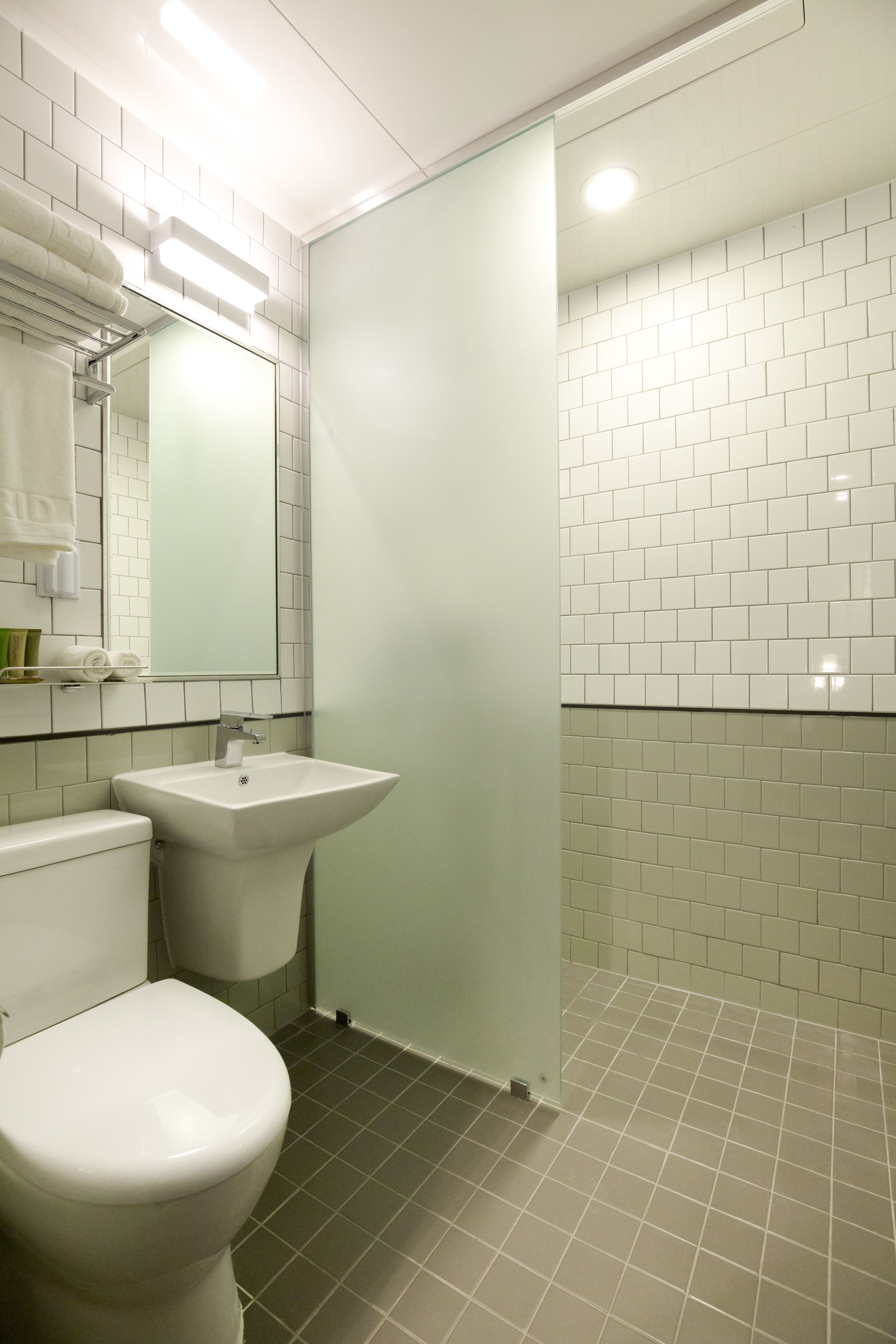 Een badkamer met toilet, wastafel en een douchecabine van glas.