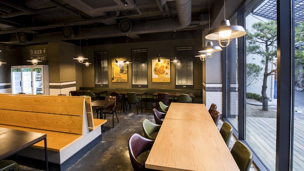 A restaurant with wooden tables and benches, large windows, and hanging pendant lights. - Grid Inn (Seoul)