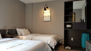 A hotel room with two beds, a bedside table with lamps, a wall-mounted light, a safe, and a suitcase. - Grid Inn (Seoul)