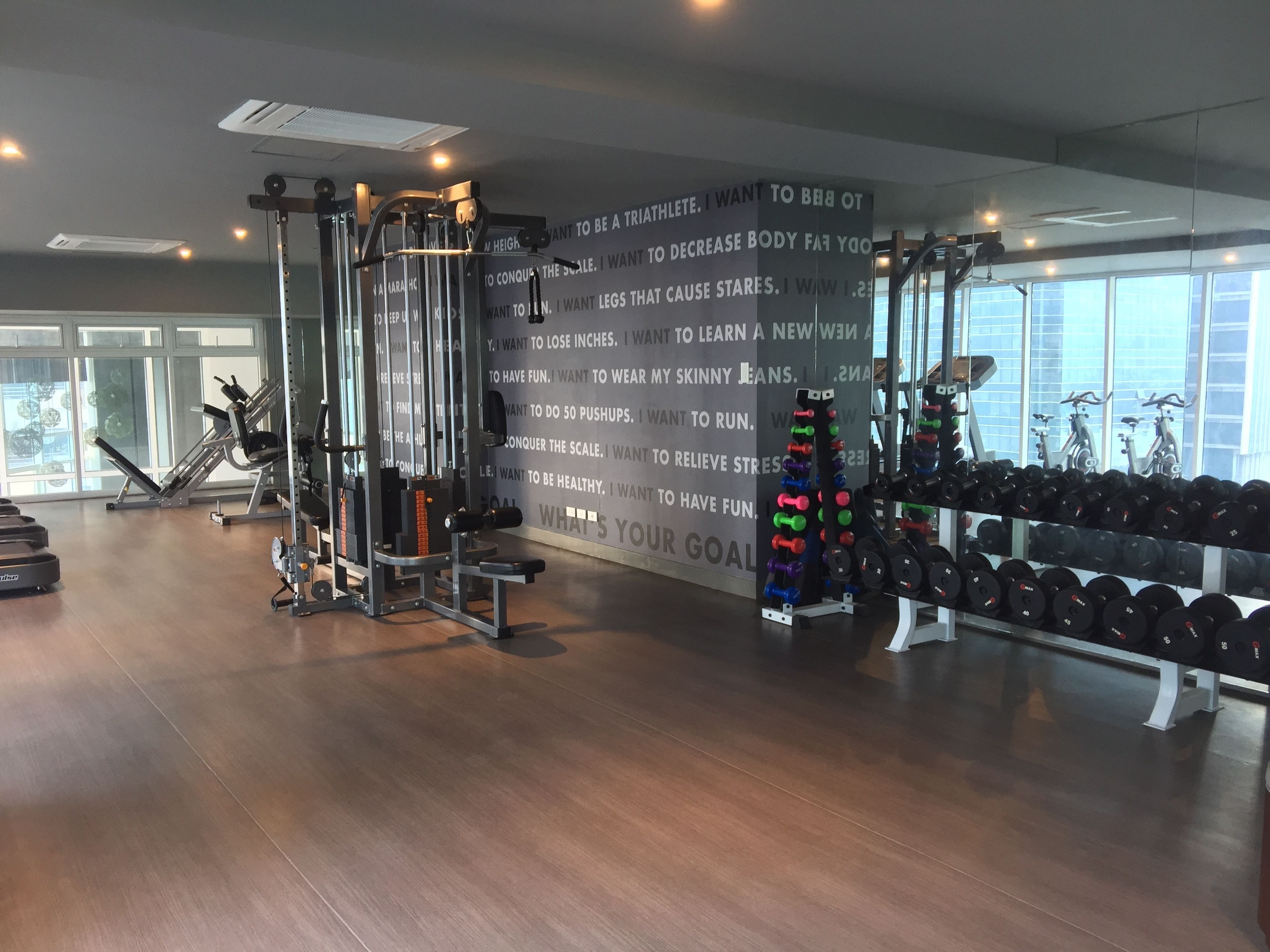 Een sportschool met fitnessapparatuur, gewichten en een motiverende muurtekst.