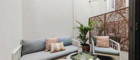 Una sala de estar moderna con un sofá gris, una mesa de centro redonda y una planta en maceta.