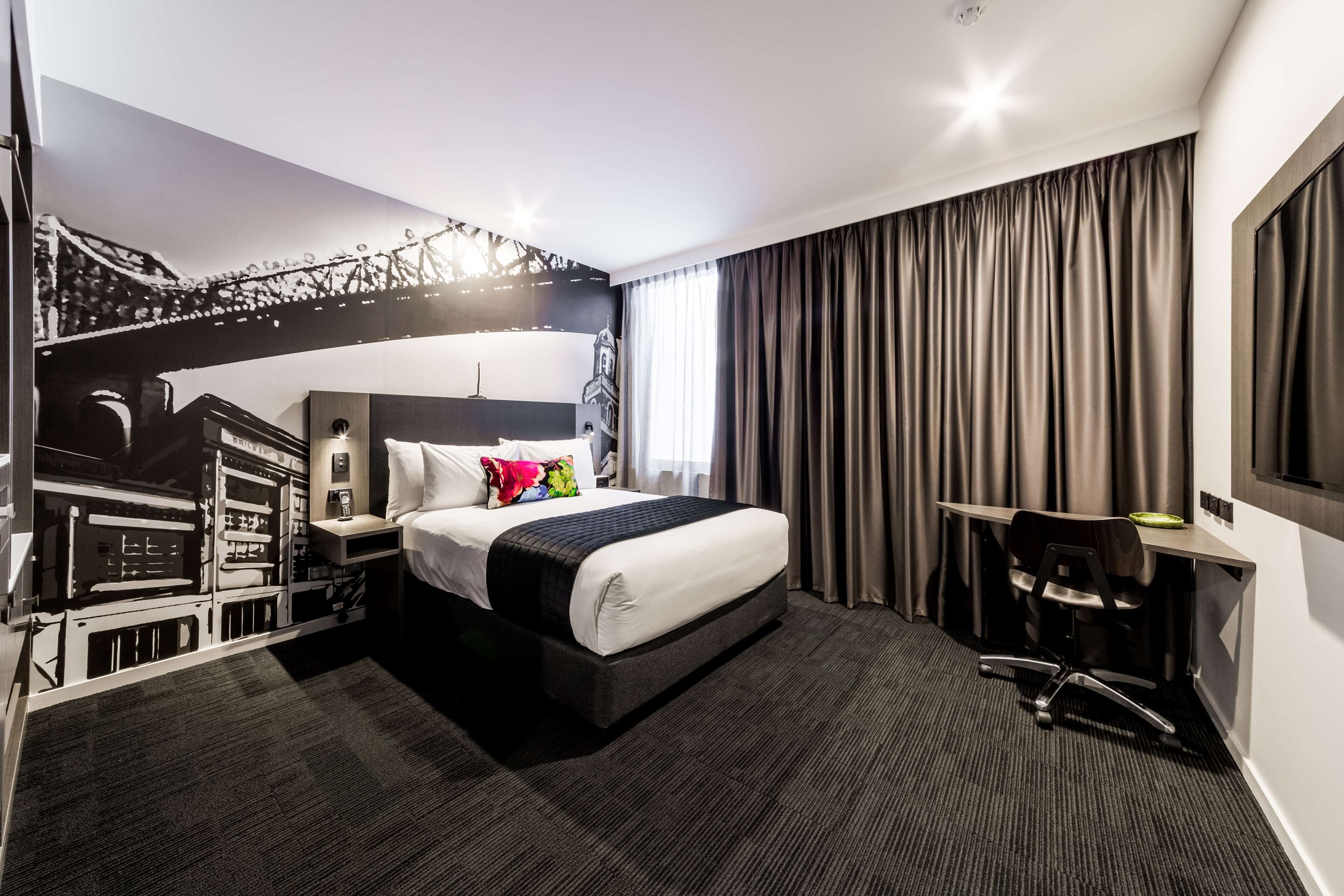 Une chambre d’hôtel moderne avec un grand lit, un bureau et une chaise.