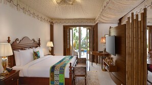 Habitación de hotel con una cama grande, televisión, escritorio con silla y vistas al exterior.
