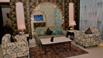 A living room with a sofa, two armchairs, a coffee table, and a patterned rug.