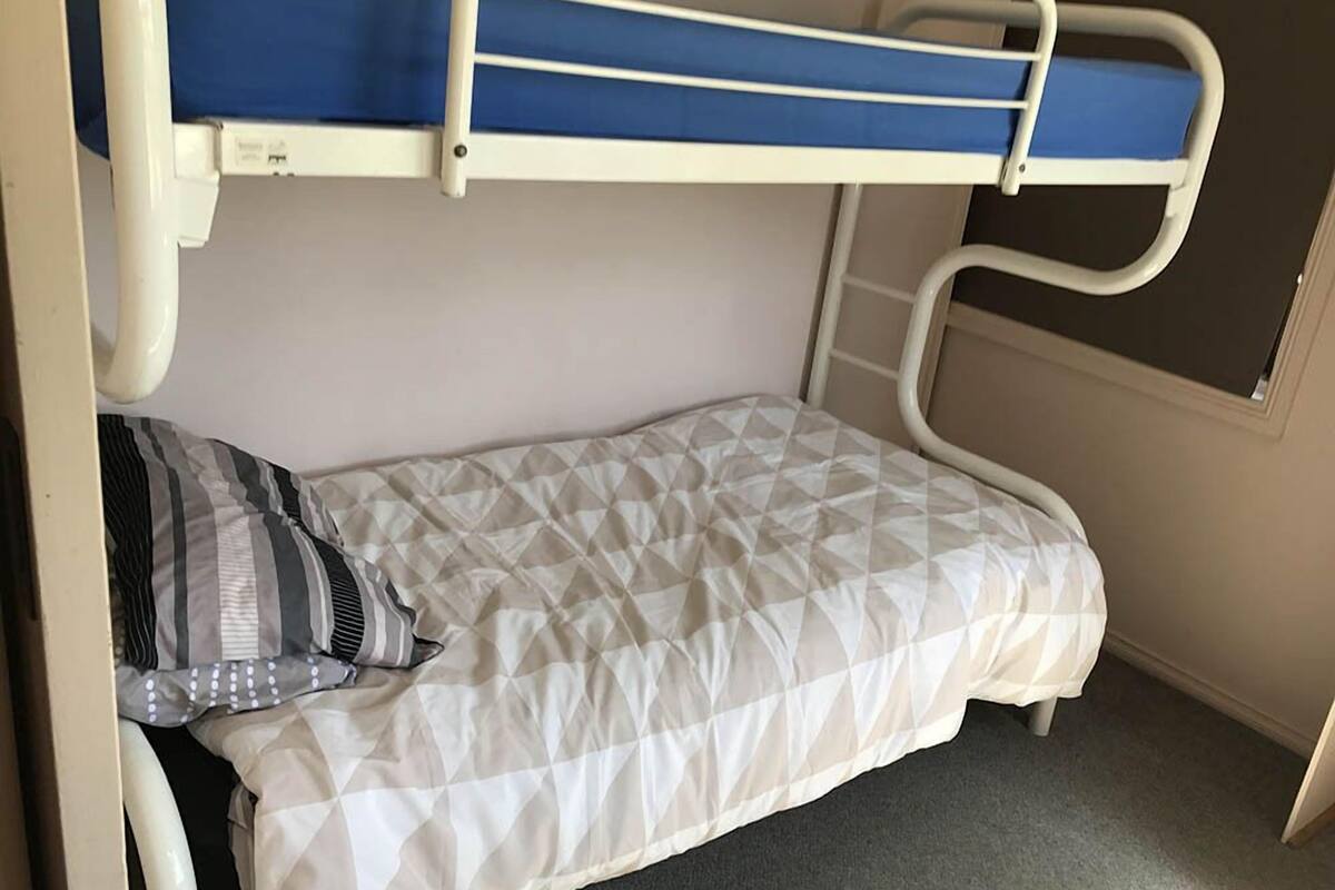 A bunk bed with a blue mattress at the top and a white mattress at the bottom.