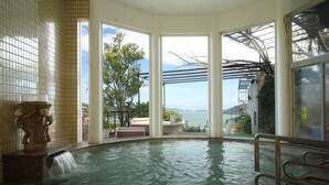 Une piscine intérieure offrant une vue dégagée sur la mer, une sculpture en pierre et une pergola avec vue panoramique.