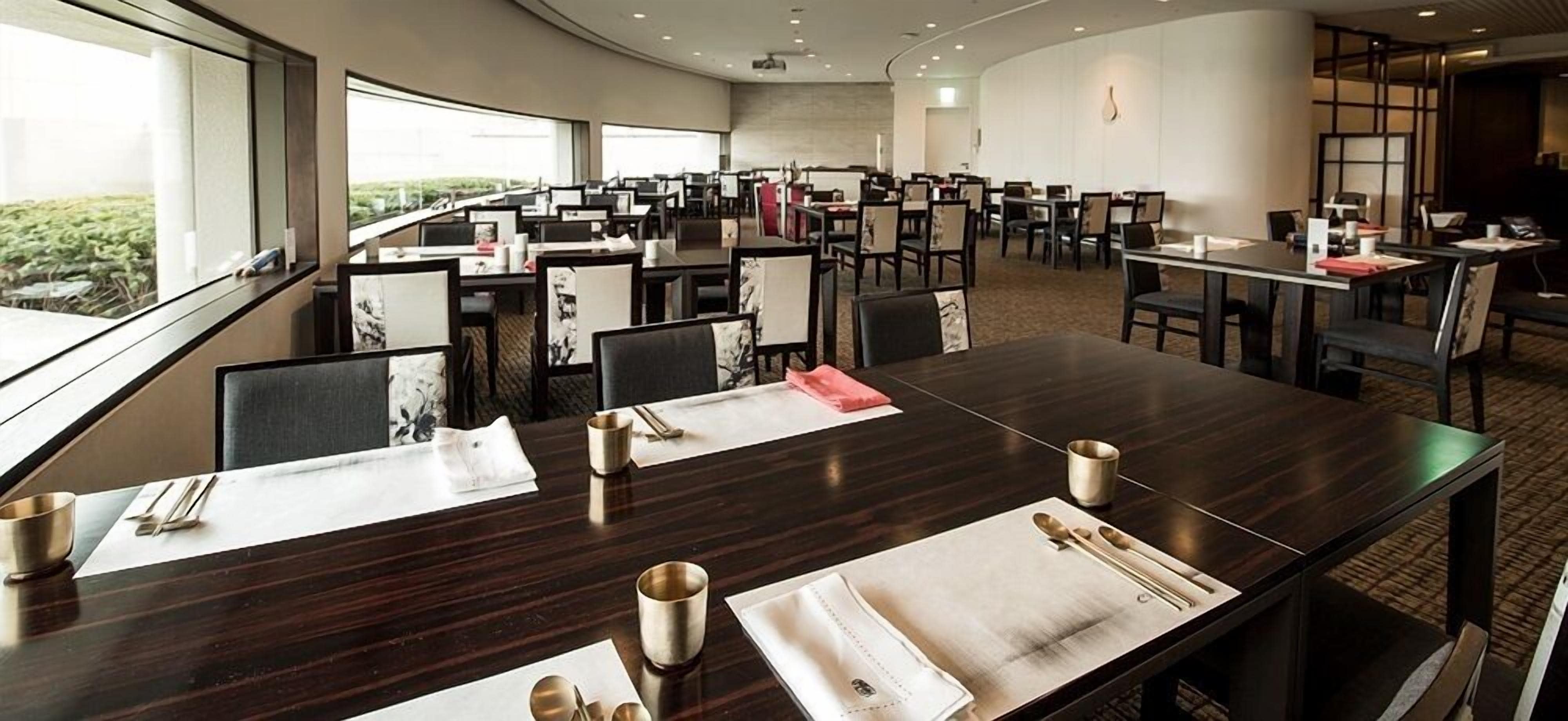 A conference room with multiple tables and chairs, arranged in a semi-circular layout.