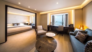 Una habitación de hotel moderna con cama, escritorio, sofá y mesa de centro.
