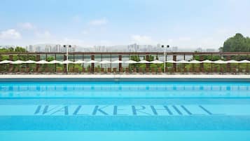 Une piscine dotée de chaises longues et de parasols, avec la silhouette de la ville en arrière-plan.