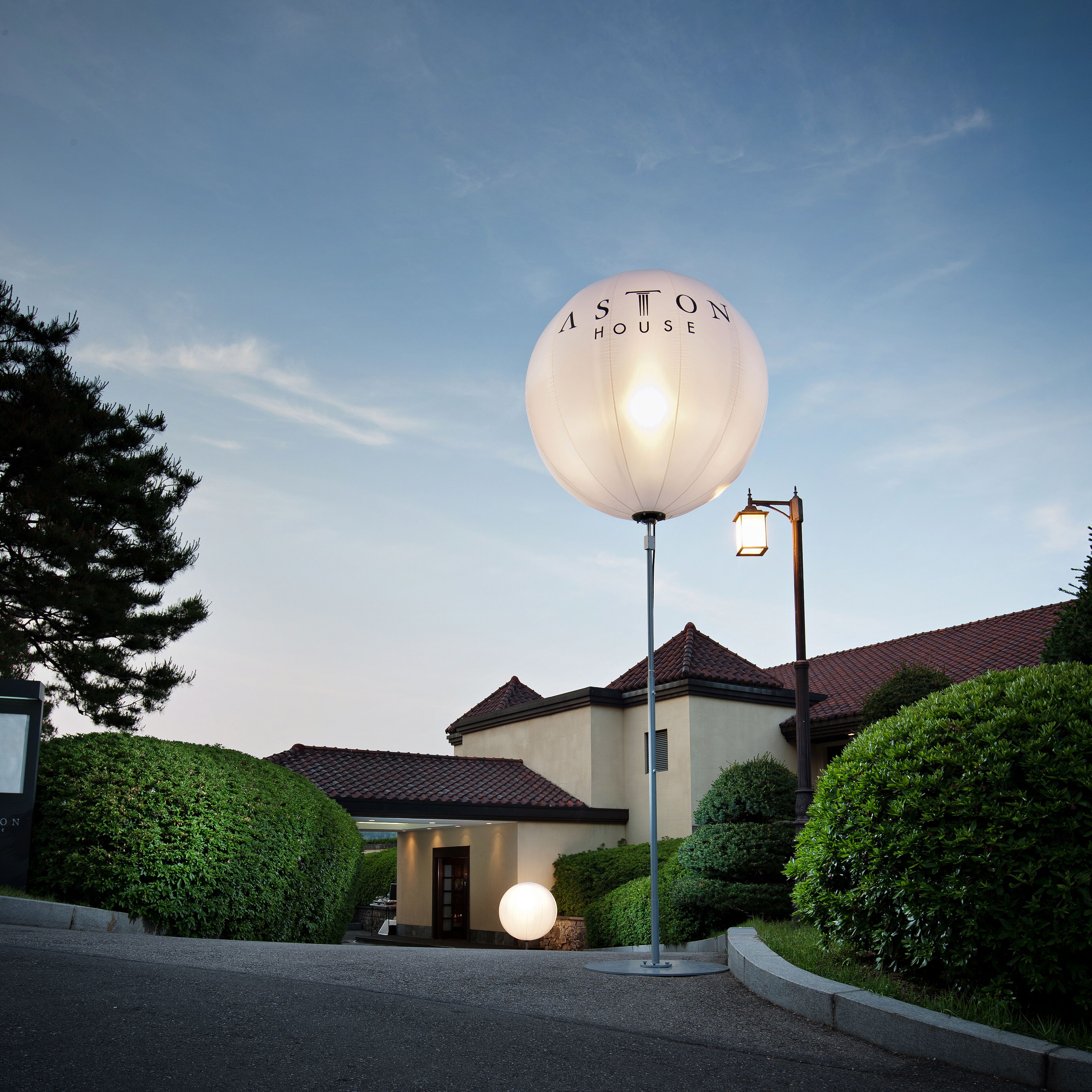 Un edificio con un letrero esférico que dice "ASTON HOUSE" y un farol.