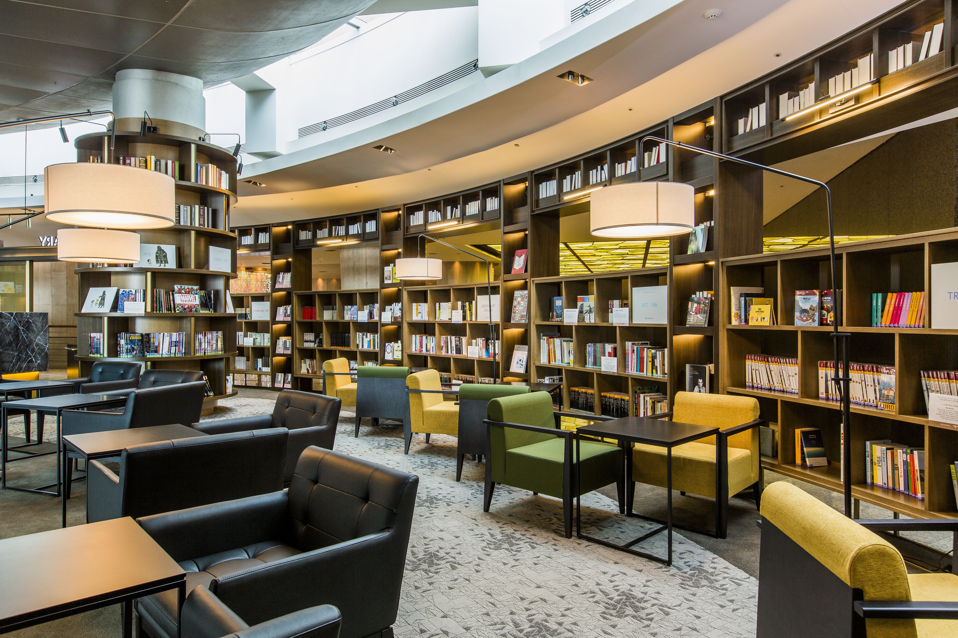 Eine moderne Bibliothek mit Bücherregalen, Sitzbereichen und Leselampen.