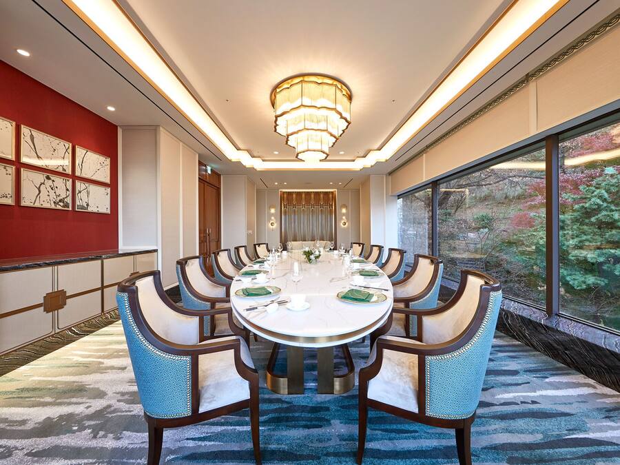 A conference room with a round table, blue chairs, and a chandelier.