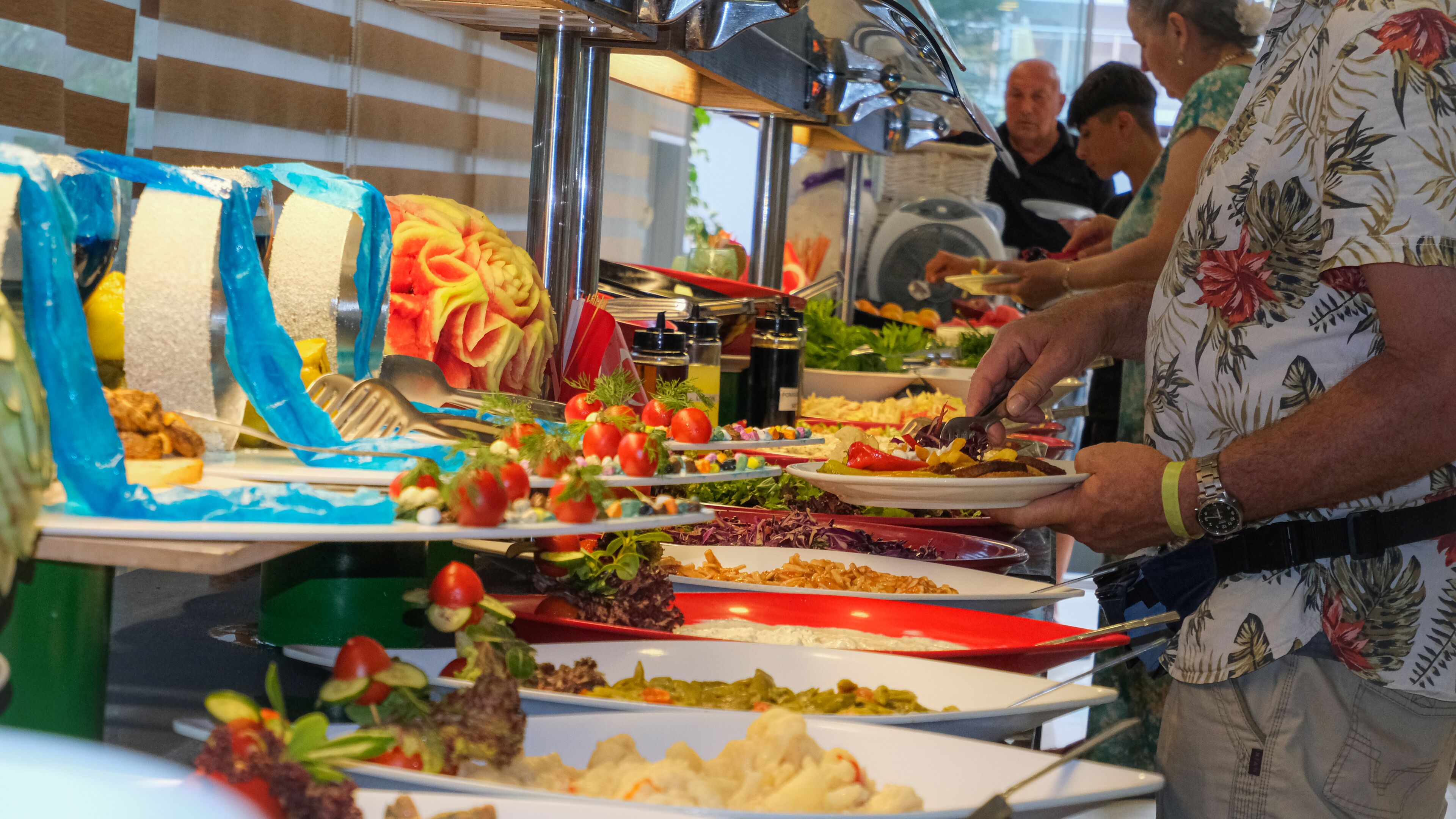 A buffet with various food items and a person serving themselves.