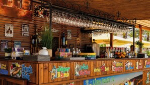 A bar area with wooden paneling, a variety of drink options, and a mural of cocktails. - Hawaii Suite Beach Hotel (Alanya)