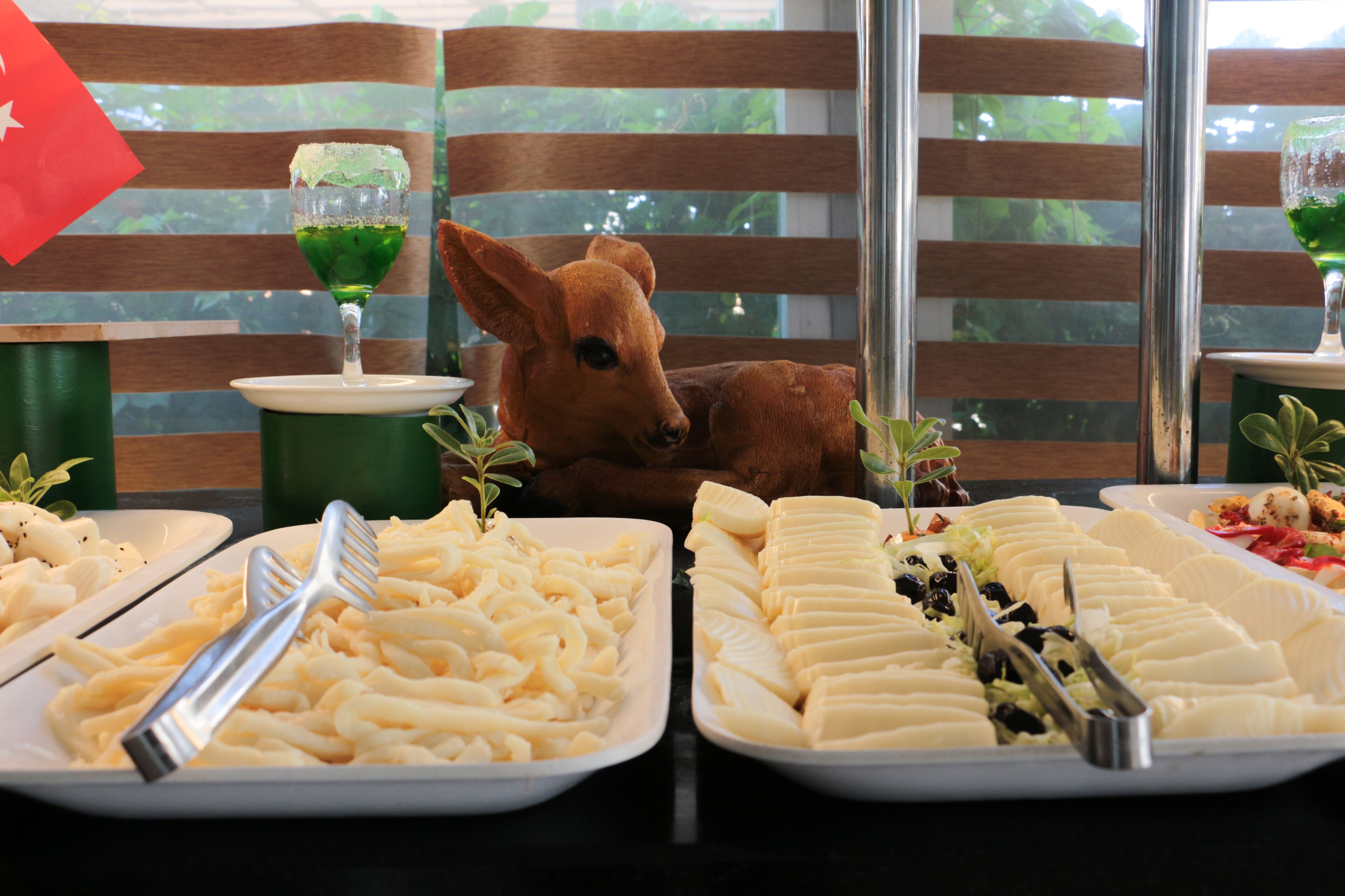 A dining table with various food platters, a glass of green beverage, and a stuffed animal.