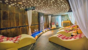A spa area with a curved ceiling, seating with blankets, a small pool, and a decorative wall. - Hawaii Suite Beach Hotel (Alanya)