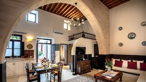 Amplia sala de estar con mesa de comedor, sofá y escalera que lleva a un nivel superior.