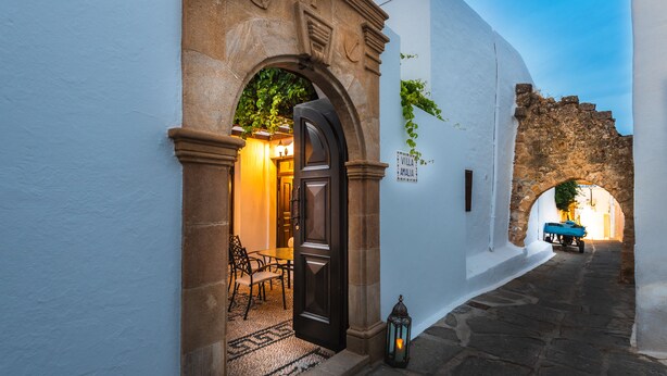 Un estrecho callejón empedrado con un arco rústico que conduce a un edificio con un cartel que dice