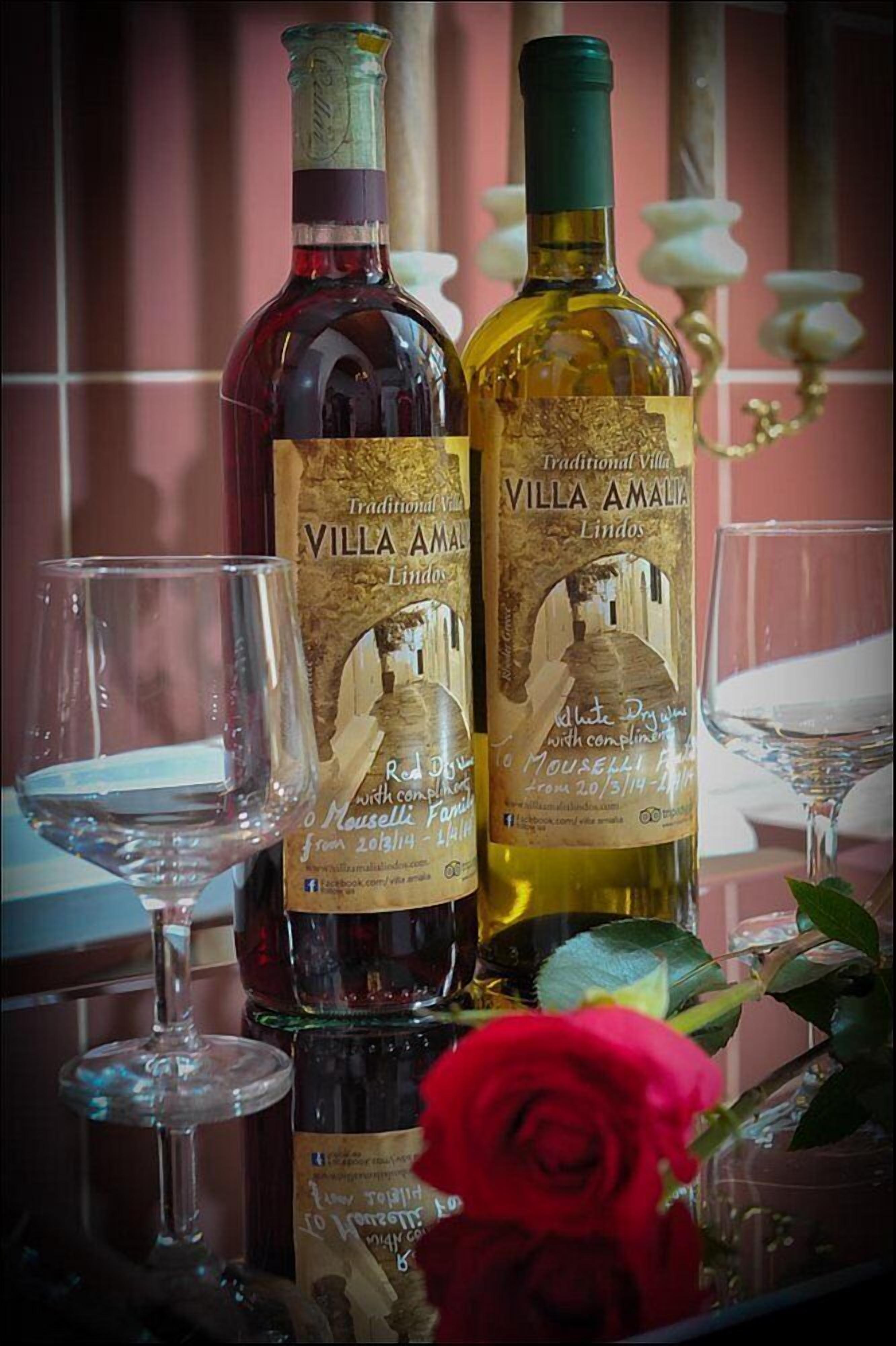 Duas garrafas de vinho Villa Amalia com etiquetas, um copo e uma rosa vermelha.