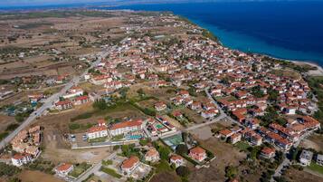 Vista aérea de una zona residencial costera con casas, carreteras y un gran edificio con piscina.