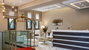 A modern hotel lobby with a reception desk, seating area, and a glass elevator. - Lagaria Apartments (Kassandra)