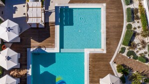 An aerial view of a resort's swimming pool area with sun loungers and umbrellas. - Lagaria Apartments (Kassandra)