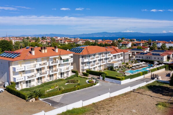 A hotel with multiple balconies, a swimming pool, and solar panels on the roofs. - Lagaria Apartments (Kassandra)