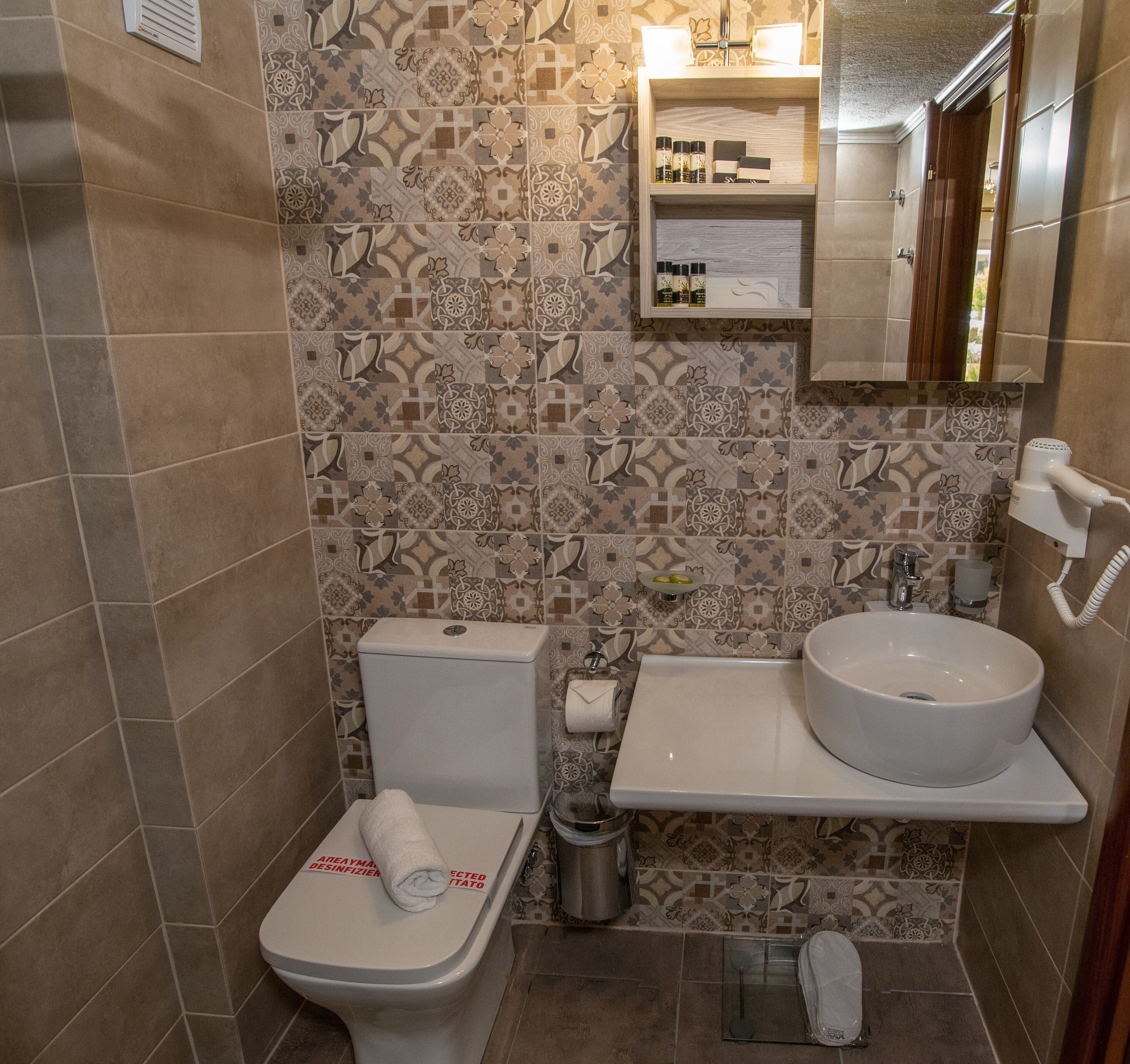 Une salle de bain avec des toilettes, un lavabo et un miroir au-dessus du lavabo.