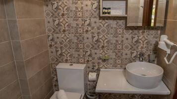 Une salle de bain avec des toilettes, un lavabo et un miroir au-dessus du lavabo.