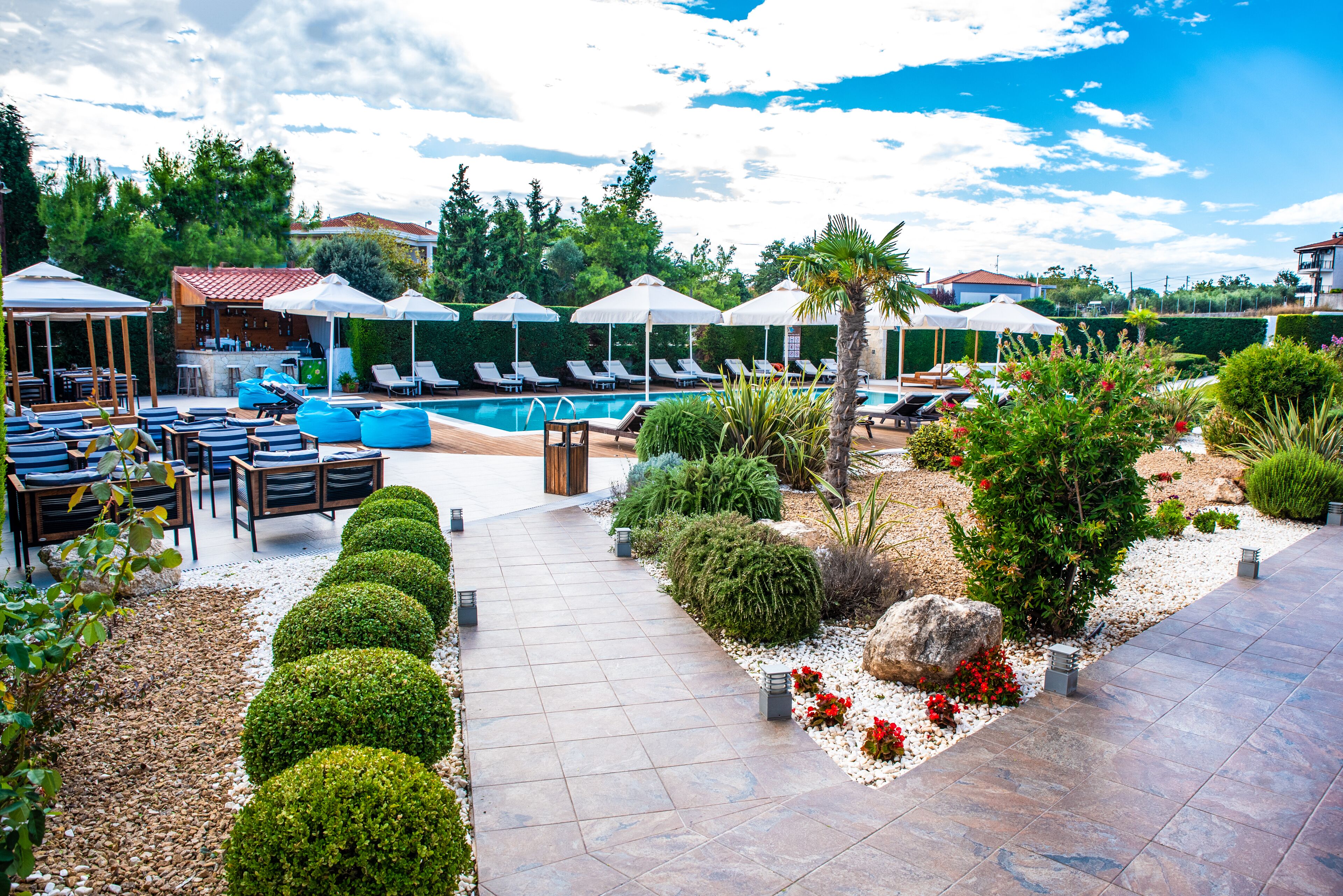 Un área de piscina con sillones de descanso, sombrillas y un bar.