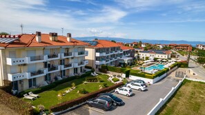 A multi-story hotel with balconies, a swimming pool, and a parking area. - Lagaria Apartments (Kassandra)