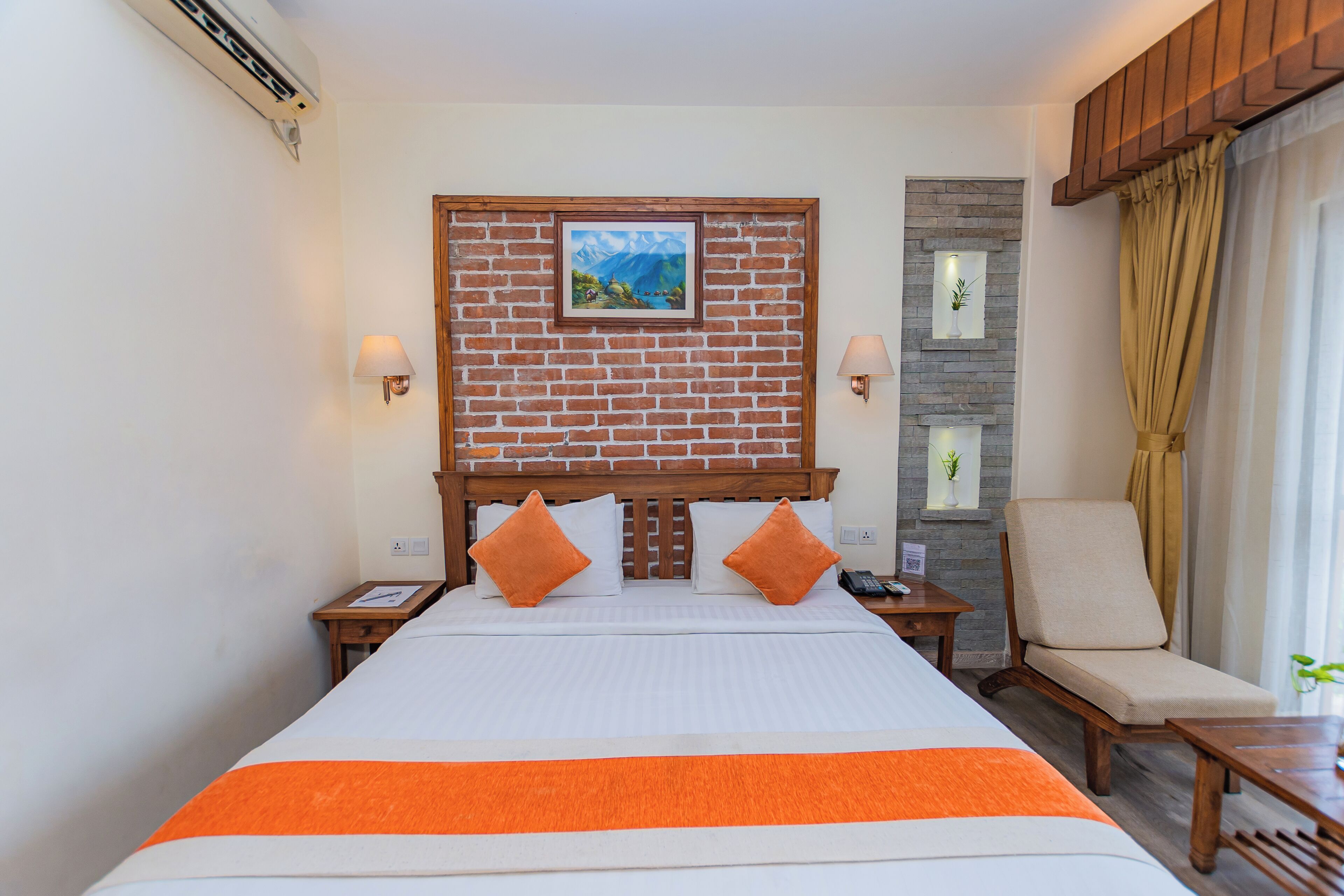 Una habitación de hotel con una cama grande, dos mesitas de noche, una silla y un televisor montado en la pared.