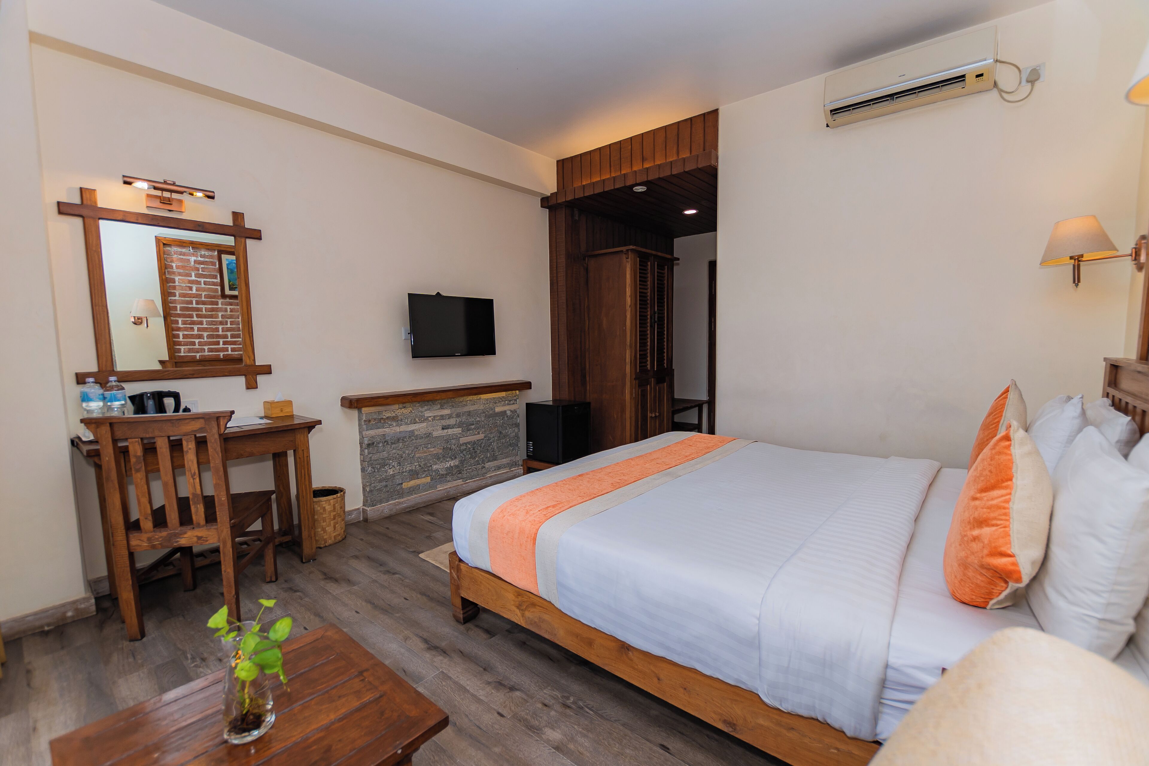A hotel room with a bed, wooden desk, and a TV mounted on the wall.