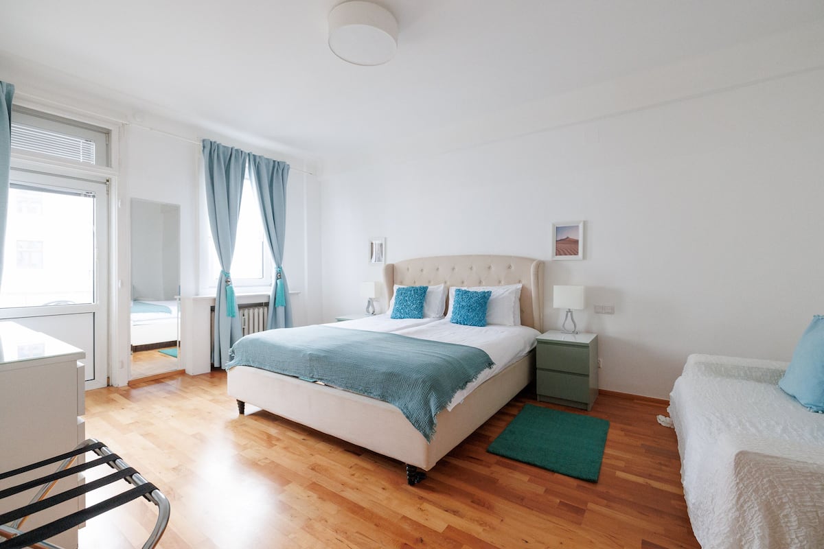 A bedroom with a bed, bedside tables, a desk, and a chair.