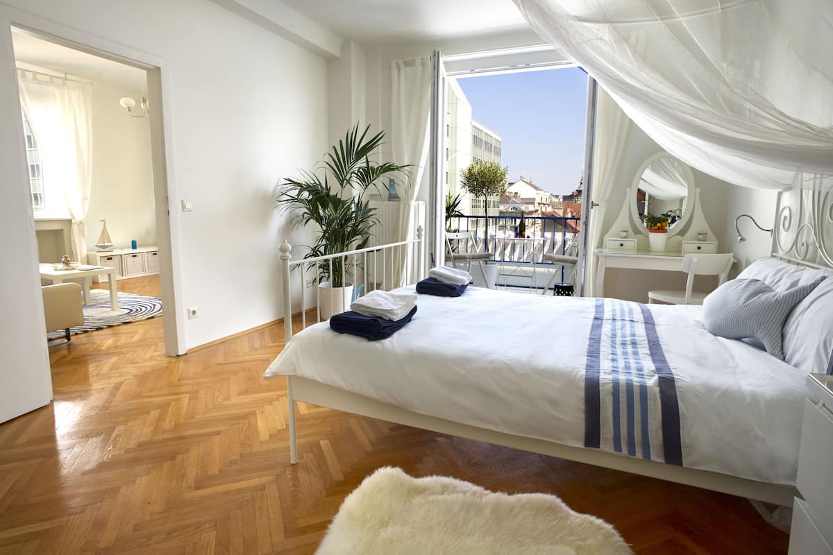 A bedroom with a bed, bedside table, and a view of the city.