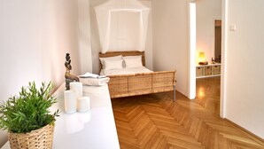 Ein Schlafzimmer mit einem Bett, einem Nachttisch mit Kerzen, einer Topfpflanze und einer Pendelleuchte.