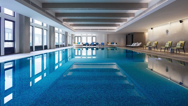 A large indoor swimming pool with clear blue water, surrounded by windows and lounge chairs. - Element Chongli (Zhangjiakou)
