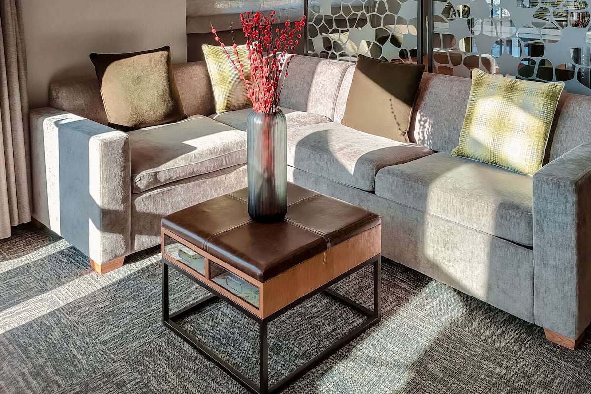 A modern living room with a sectional sofa, a coffee table, and a decorative vase with red branches.
