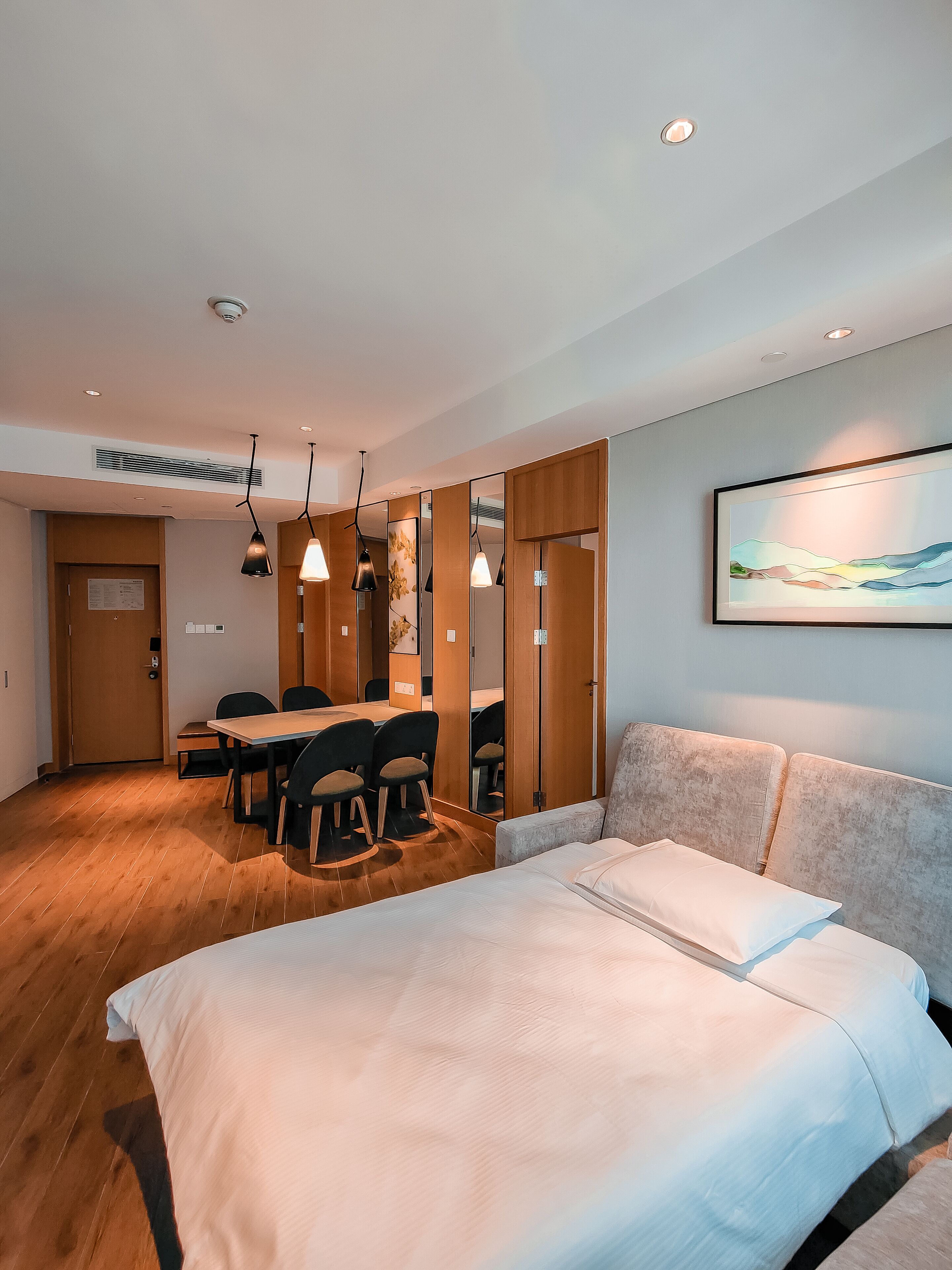 Una habitación de hotel moderna con una cama grande, un comedor y una sala de estar.